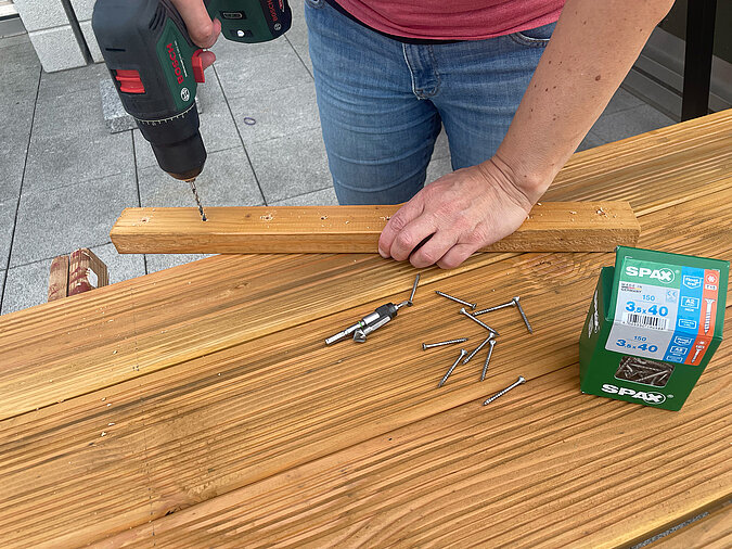 Grillplatz für die Terrasse bauen: Vorbohren der Ablagebretter mit Akkuschrauber für eine stabile Verschraubung – essenzieller Schritt beim DIY-Bau einer wetterfesten Grillstation.