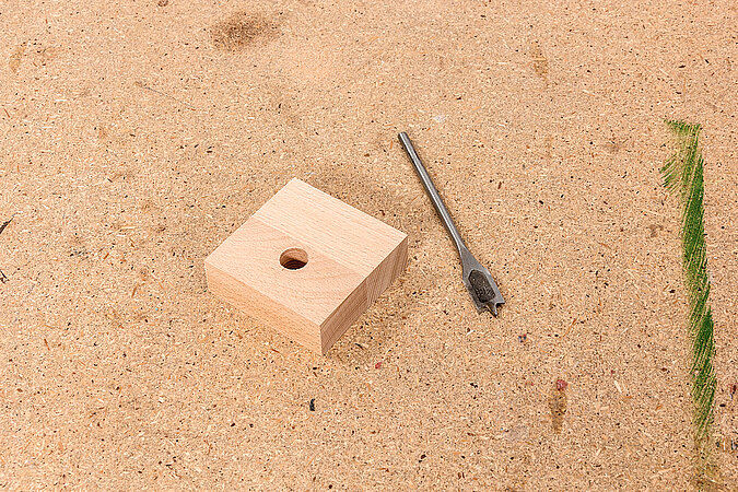Wandgarderobe aus Kickerfiguren bauen mit Holzklotz und Bohrer als Abstandshalter für die stabile Wandmontage der DIY Garderobe
