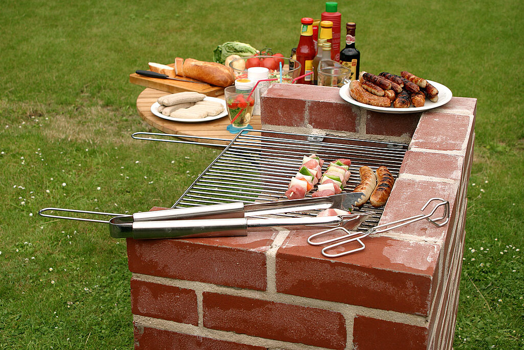 Auf einem selbstgemaiertern Gartengrill ist das Grillgut appetitlich drapiert