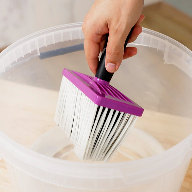 ChatGPT: Wände richtig tapezieren: Tapezierbürste wird mit Kleister aus einem Eimer vorbereitet – ideal für gleichmäßiges Auftragen an Wand oder Tapete