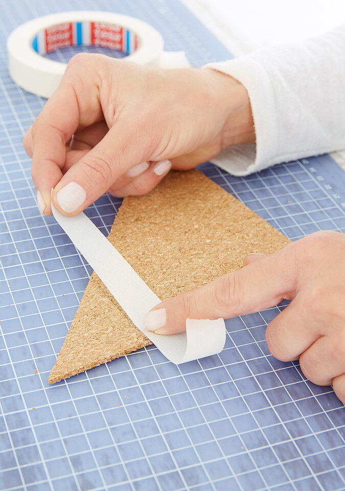 Für eine Pinnwand aus Kork im Fuchsdesign werden die Akzente auf der Korkplatte abgeklebt 