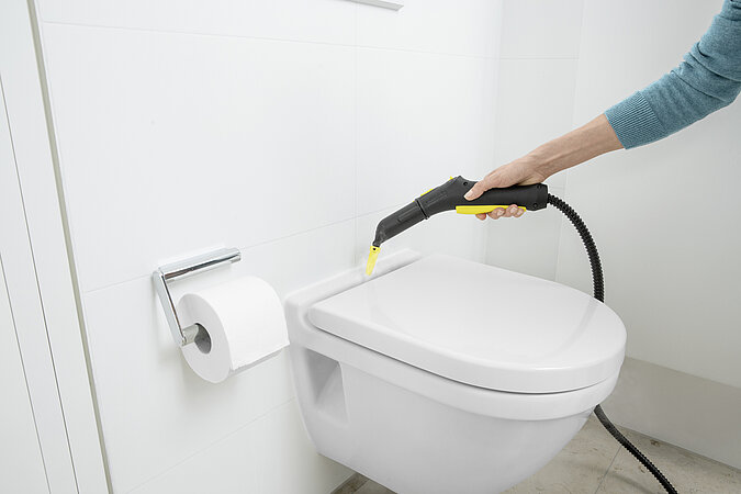 Toilette wird mit Dampfreiniger in der Ritze zwischen Befestigung und Sitz gereinigt