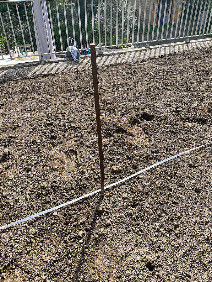 Tipi aus Weiden bauen mit einem abgesteckten Kreis auf lockerer Erde als Basis für das Gartenprojekt