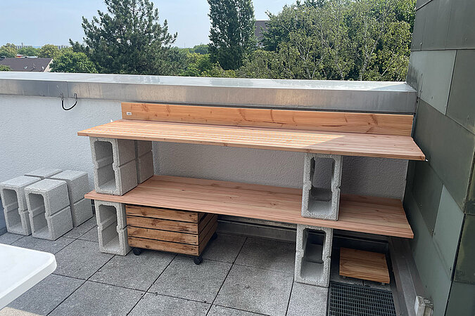 Grillplatz für die Terrasse bauen: DIY-Grillstation aus Holzbohlen und Hohlblocksteinen mit zwei stabilen Ebenen – praktische Bauweise für eine wetterfeste Outdoor-Küche oder Arbeitsfläche auf der Terrasse.