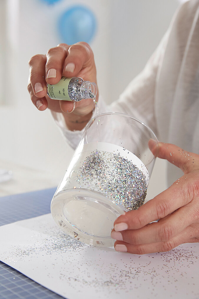 Silbernes Glitzerpulver wird auf das doppelseitige Klebeband gestreut