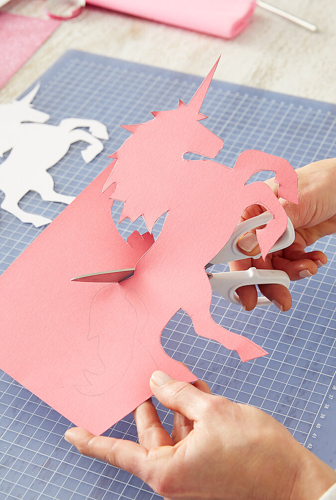 Für eine Schultüte wird ein Einhorn aus rosa Folie ausgeschnitten