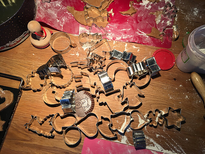 Lernturm für Kinder bauen und gemeinsam fantasievoll ausgestochene Weihnachtskekse dekorieren, bunte Plätzchen auf Backblechen und Arbeitsfläche verteilt
