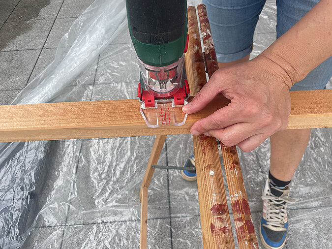 Grillplatz für die Terrasse bauen: Zuschneiden einer Holzlatte mit der Stichsäge – präzise Ausführung beim DIY-Projekt für eine maßgeschneiderte Grillstation im Außenbereich.