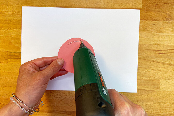Einschulung Orden basteln mit Heißkleber zum Befestigen der Rückseite der Papierrosette
