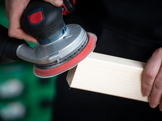 Lernturm für Kinder bauen und zugeschnittene Holzleisten mit einem Exzenterschleifer sauber glätten für eine sichere Oberfläche
