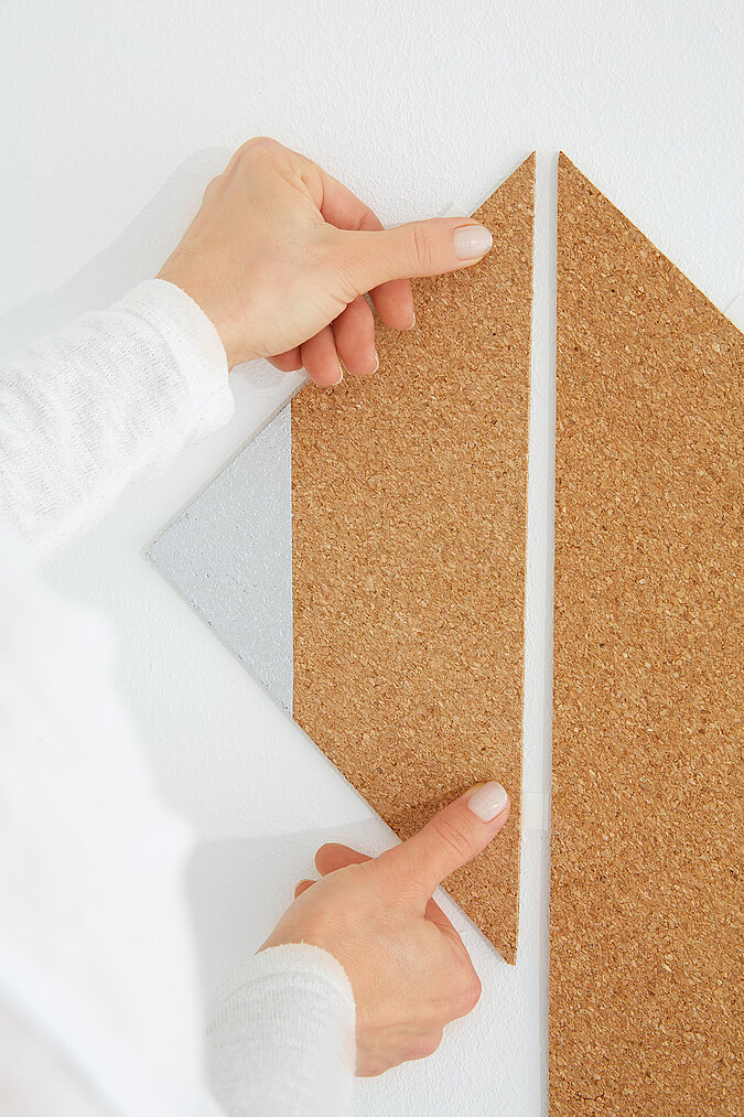   Eine Pinnwand aus Kork im Fuchsdesign werden mit Powerstrips an die Wand geklebt