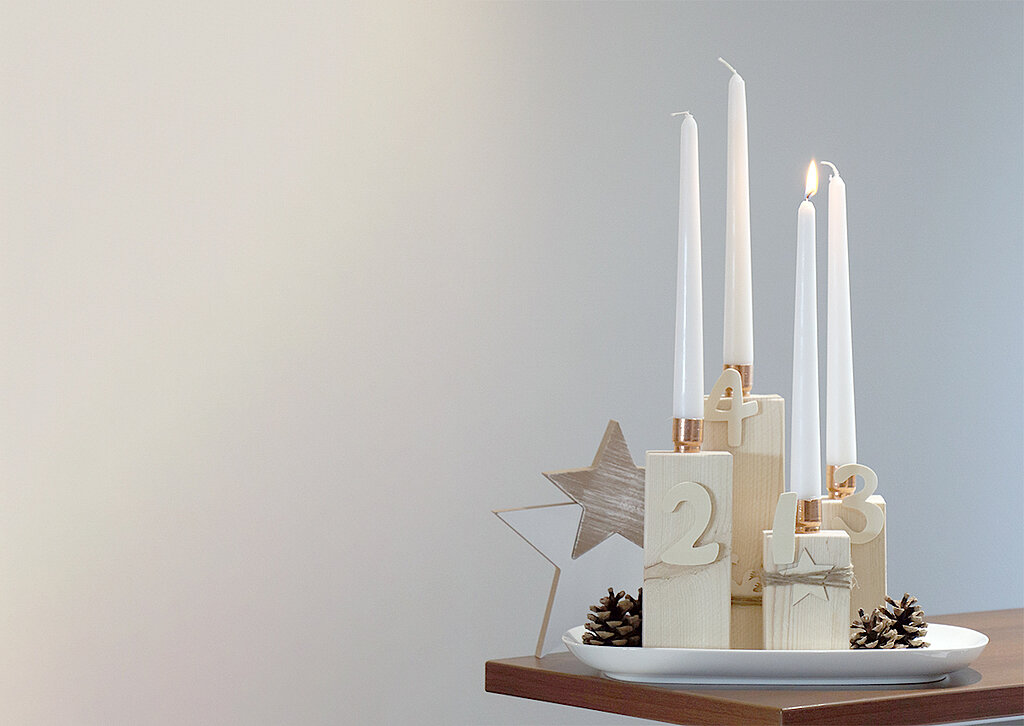 Adventskranz aus Kanthölzern steht schön dekoriert auf dem Esstisch