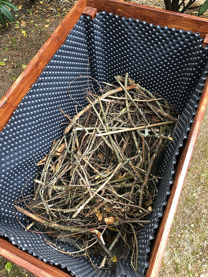 Hochbeet im Trend: Unterste Schicht aus groben Ästen und Zweigen für eine optimale Drainage