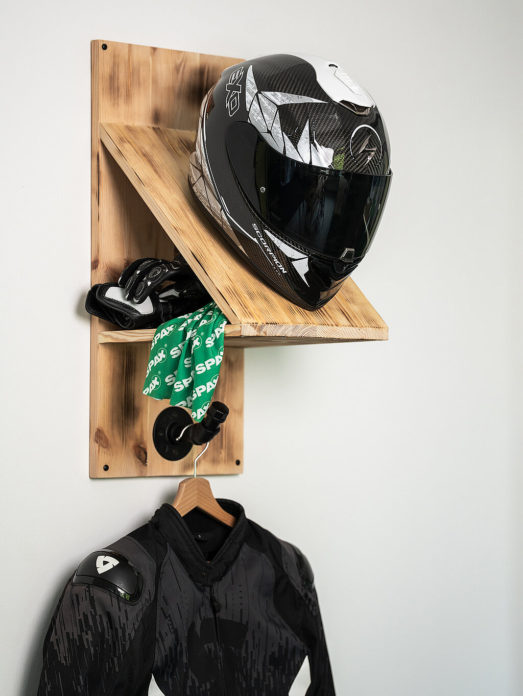 Selbstgebaute Helm-Garderobe aus angeflämmten Leimholz, bestückt mit Helm, Motorradhandschuhen, SPAX-Halstuch und Mottorradjacke