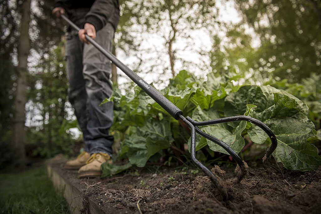 Der Boden wird mit einem Rechen aufgelockert