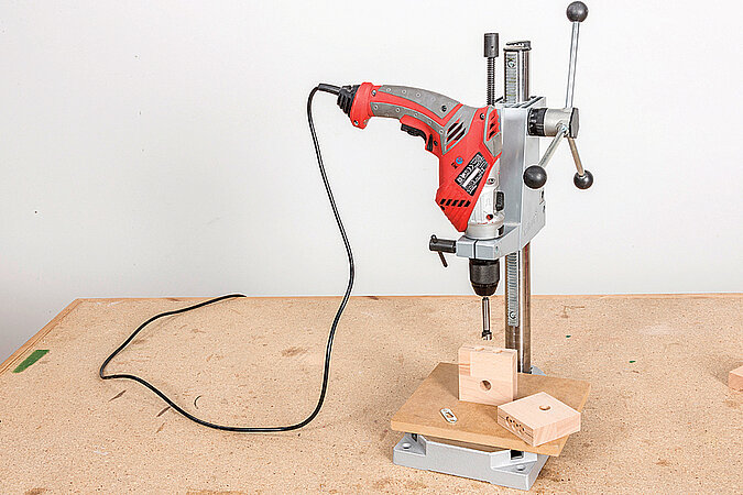 Wandgarderobe aus Kickerfiguren bauen mit Bohrmaschine beim präzisen Bohren der Befestigungslöcher für die Wandhalterung