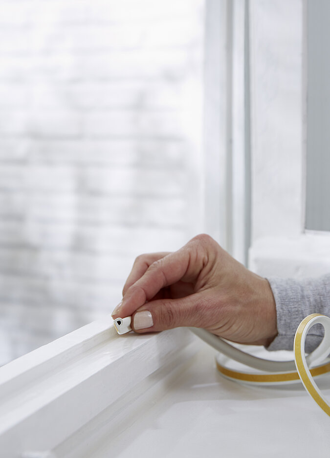 Hand am Fenstergriff eines modernen Fensters als Maßnahme, um ein Haus energetisch zu sanieren und die Energieeffizienz zu steigern.