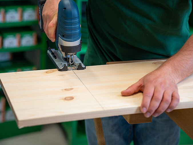 Halloween-Laternen selber bauen: Holz wird mit einer Stichsäge ausgeschnitten, um das Gesichtsmotiv der Laterne zu formen