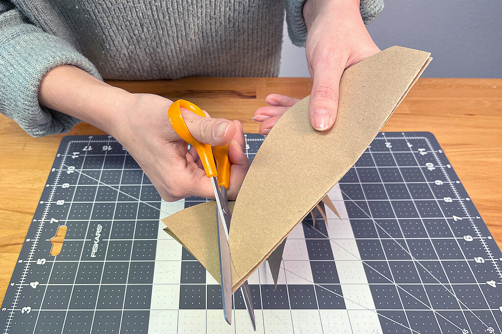 Eine ovale Form wird aus einem Blatt Bastelpapier ausgeschnitten