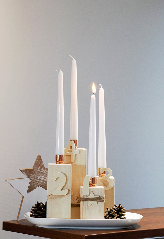 Adventskranz aus Kanthölzern steht schön dekoriert auf dem Esstisch