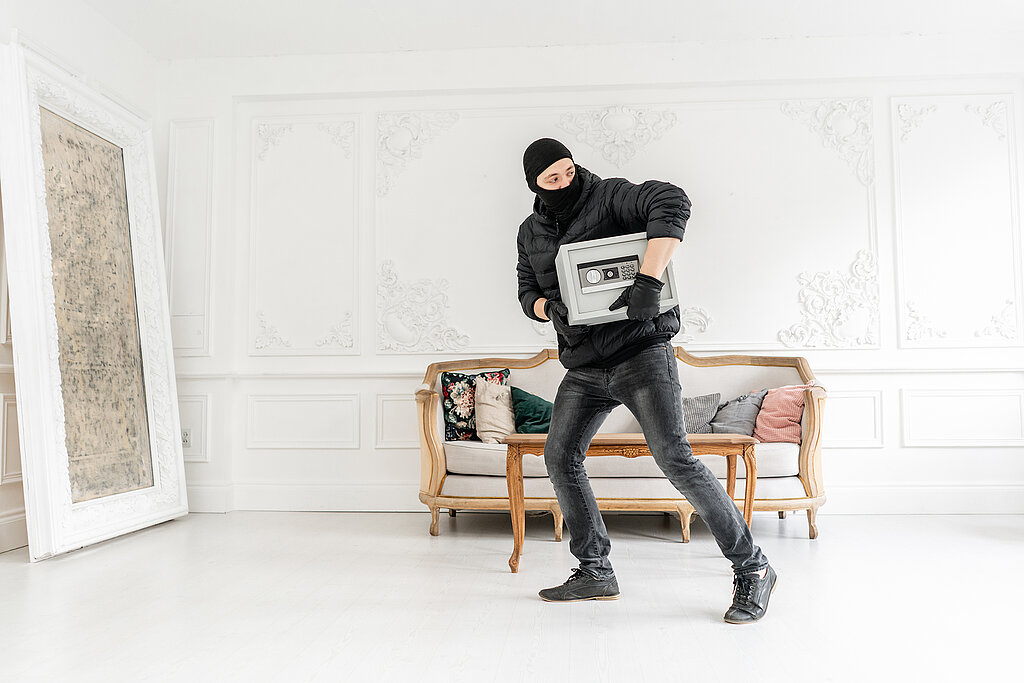 Tresor für zuhause: Schutz für Wertsachen & Dokumente Einbrecher trägt gestohlenen Safe aus Wohnraum und verdeutlicht Risiko ohne ausreichende Sicherung