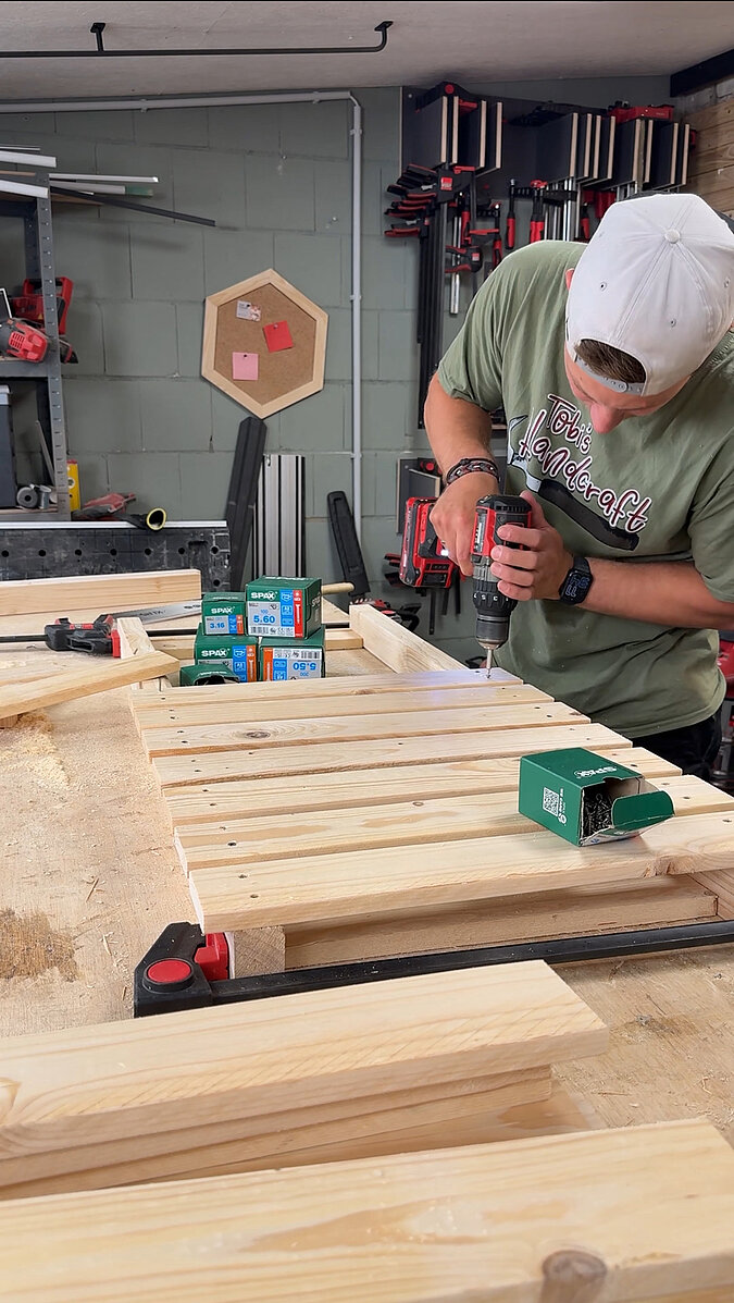 Mobilen Grillwagen bauen beim Verschrauben der Holzlatten mit dem Akkuschrauber, Montage der Arbeitsfläche und Ablagen für den selbstgebauten Grillwagen in der Werkstatt