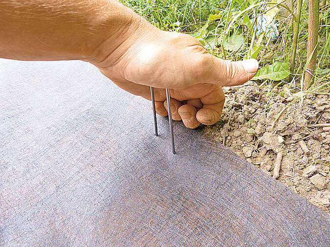 Holzdeck: Vlies mit Befestigungshaken fixieren