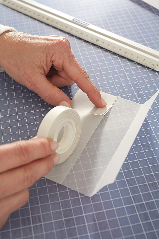 Auf die eine Seite des Transparentpapiers wir ein stück doppelseitiges Klebeband geklebt