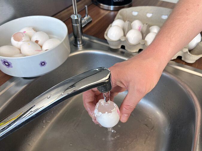 Osterkranz aus Eierschalen basteln mit gründlichem Ausspülen der leeren Eierschalen unter fließendem Wasser
