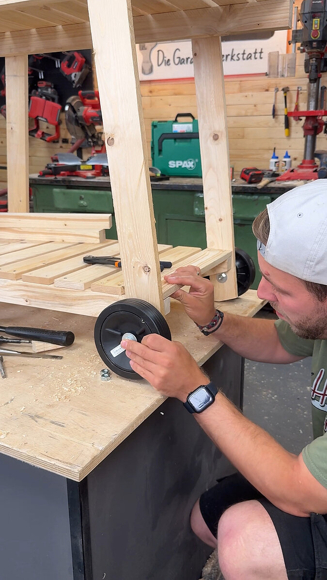 Mobilen Grillwagen bauen beim Montieren der Lenkrolle mit Schrauben am Holzgestell, Befestigung der Rollen für einen leicht beweglichen selbstgebauten Grillwagen