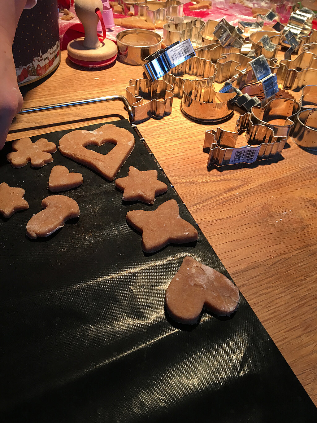 Lernturm für Kinder bauen und gemeinsam fantasievoll ausgestochene Weihnachtskekse dekorieren, bunte Plätzchen auf Backblechen und Arbeitsfläche verteilt