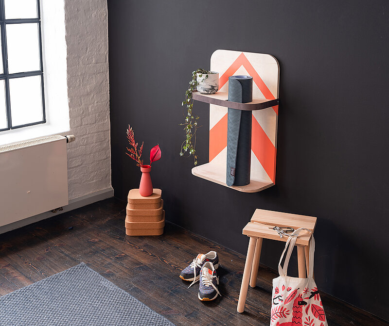 DIY-Wandregal für Yogamatte in modernem Wohnraum, montiert an schwarzer Wand mit dekorativen Accessoires.
