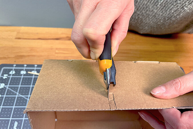 Für den Spieß der Ostereier-Malstation wird ein Schlitz in die Seitenwand mit dem Cuttermesser geschnitten