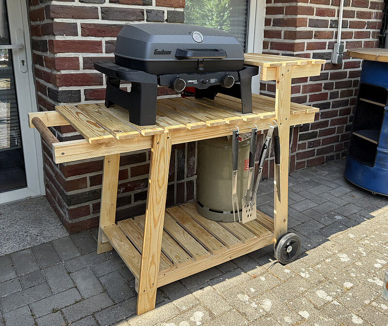 Mobilen Grillwagen bauen aus Holz mit integrierter Grillfläche, Ablageflächen und Rollen, selbstgebauter mobiler Grillwagen auf der Terrasse vor einer Hauswand