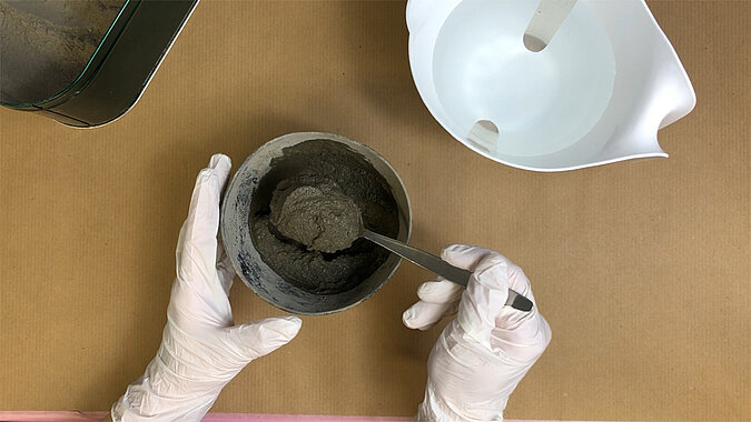 Türstopper aus Beton selber machen – Beton in der Form wird mit einem Löffel glattgestrichen, sorgfältiger Arbeitsschritt für eine ebene Oberfläche beim DIY-Türstopper