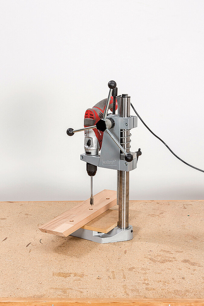 Wandgarderobe aus Kickerfiguren bauen mit Säulenbohrmaschine beim Bohren der Löcher für die Kickerstangen im Holzrahmen