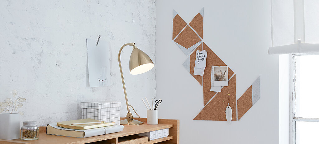 Eine selbstgebastelte Pinnwand aus Kork im Fuchsdesign hängt neben einem Schreibtisch an der Wand