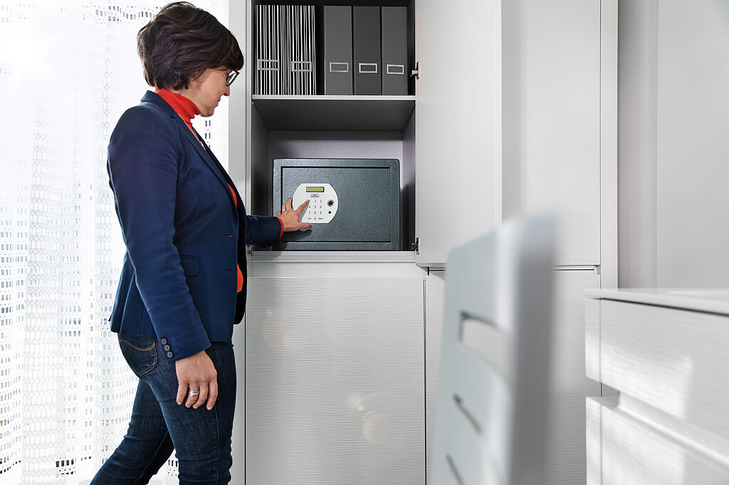 Tresor für zuhause: Schutz für Wertsachen & Dokumente Person öffnet elektronischen Safe im Wohnschrank zur sicheren Aufbewahrung wichtiger Unterlagen
