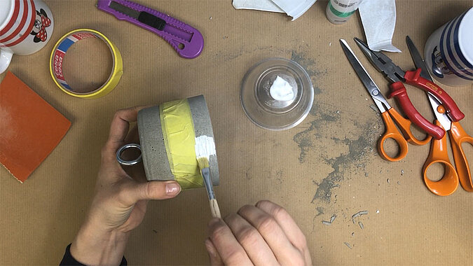 Türstopper aus Beton selber machen – abgeklemmter Beton-Türstopper wird mit weißer Farbe und Pinsel bemalt, kreativer DIY-Schritt zum Gestalten eines modernen Türstoppers aus Beton