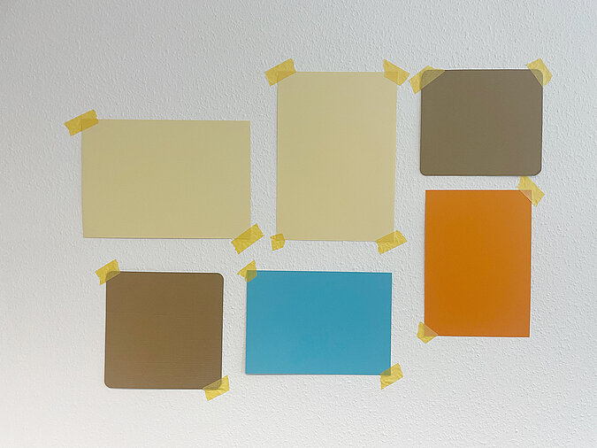 Um die Bildanordnung vor dem Bohren zu überprüfen, werden Papierschablonen mit Kreppband an der Wand befestigt