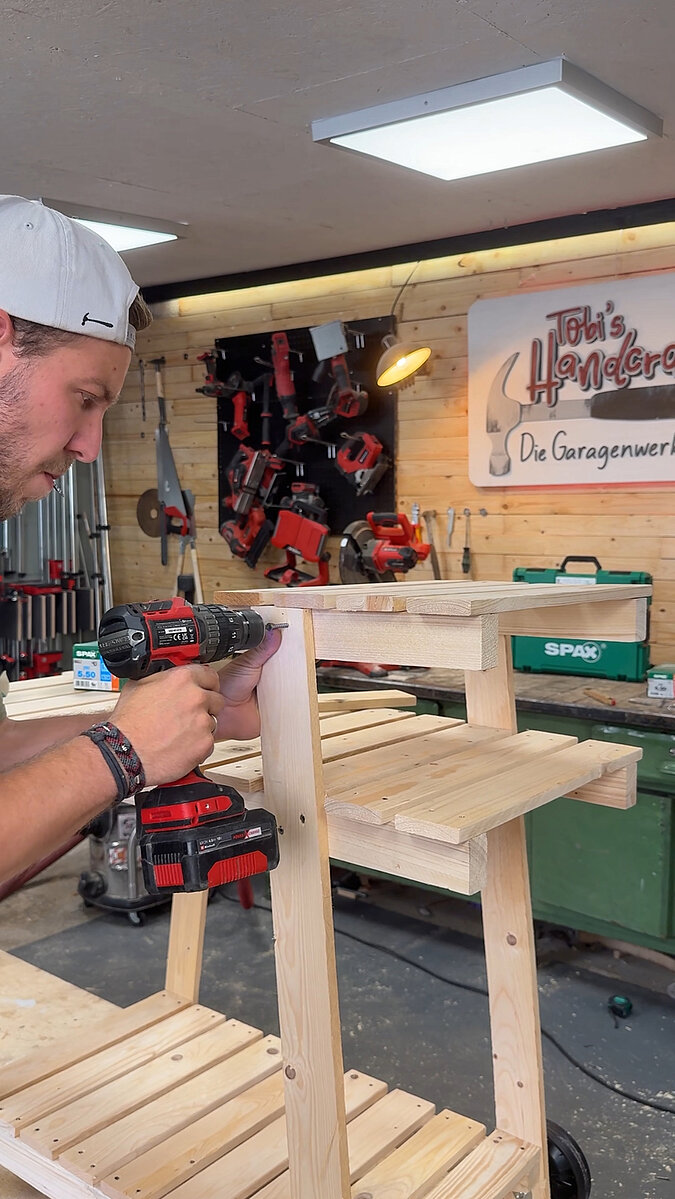 Mobilen Grillwagen bauen beim Verschrauben der oberen Ablage am Holzrahmen, Montage der zusätzlichen Arbeitsfläche für den funktionalen mobilen Grillwagen