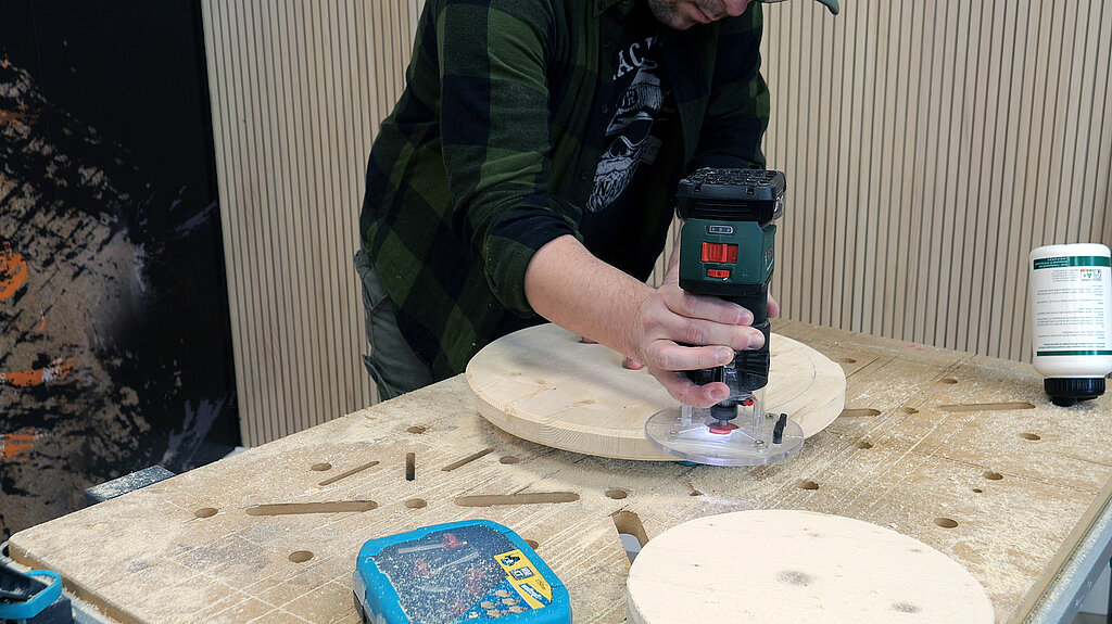 Eine runde Holzplatte wird mit einer Oberfaese geglaettet