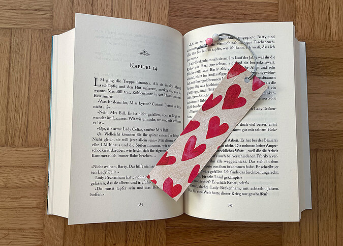 Upcycling aus TetraPak - Lesezeichen mit Herzmotiv liegt im aufgeklappten Buch