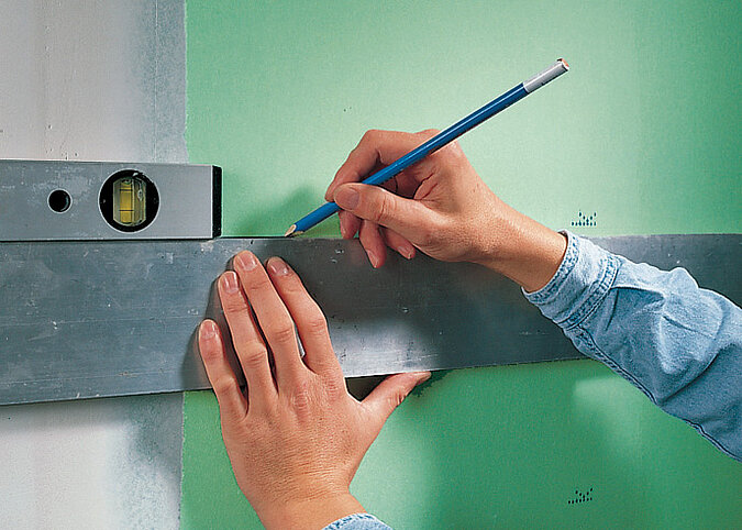 Fliesen an die Wand kleben exaktes Anzeichnen der Fliesenhöhe mit Wasserwaage und Bleistift für eine gerade Verlegung