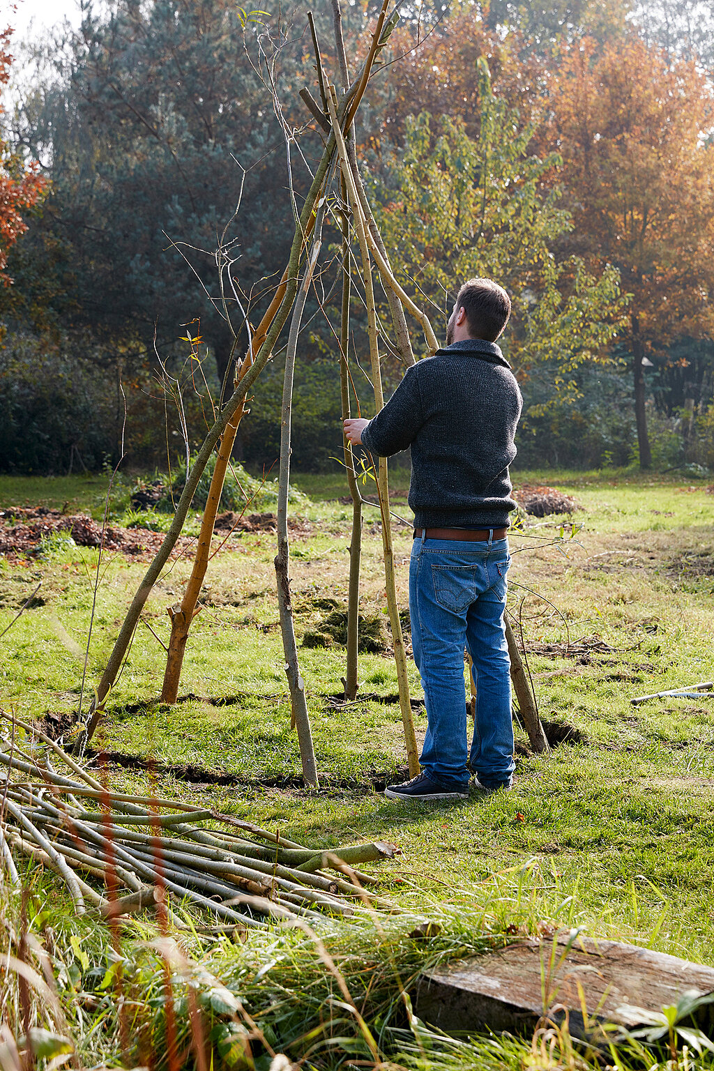 Tipi aus Weiden bauen mit aufgestellten Weidenstangen, die von Hand fixiert werden, um das Grundgerüst der Naturkonstruktion zu formen