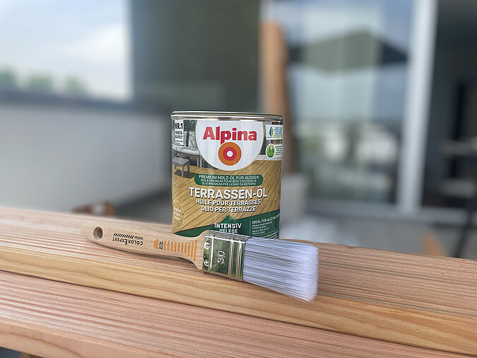 Grillplatz für die Terrasse bauen: Auf zwei Terrassendielen aus Douglasie steht eine Terrassenöl-Farbdose und ein passender Pinsel