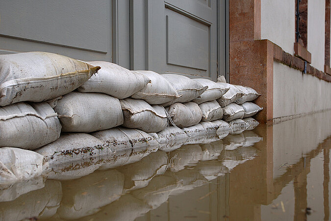 Sandsäcke liegen vor einer Tür und halten Hochwasser ab