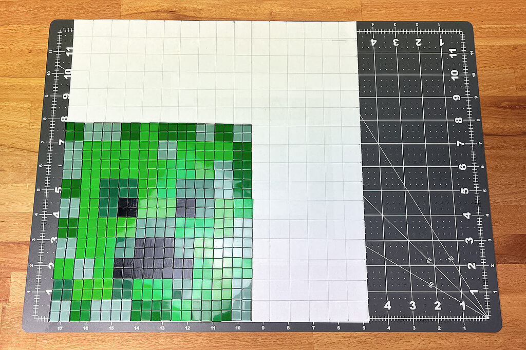 Creeper-Deko-Leuchte basteln mit aufgelegten grünen und schwarzen Mosaiksteinen nach Pixelvorlage zur Darstellung des Creeper-Gesichts