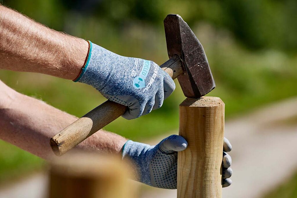 Holzzaun streichen – Pfosten mit Hammer ausrichten und vorbereiten für die Montage eines stabilen MetallzaunsHolzzaun streichen – Zaun reparieren, Pfosten mit Hammer ausrichten und vorbereiten für die Montage eines stabilen Zauns