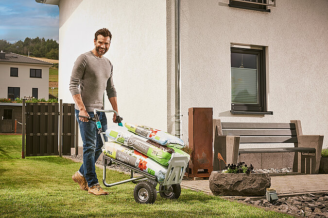 Mann transportiert Blumenerde auf Transportkarre